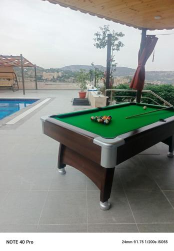 a pool table sitting next to a swimming pool at panorama tal elroman chalet in Tal‘at ar Ruzz