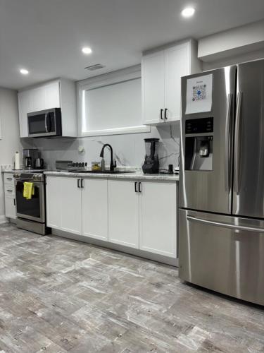 a kitchen with white cabinets and a stainless steel refrigerator at Entire 2 Bedroom Apartment in Kitchener in Kitchener
