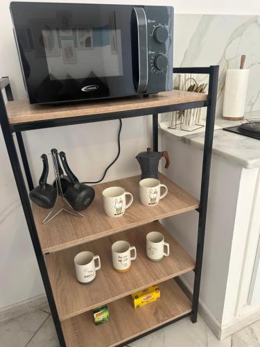 a shelf with four coffee cups and a microwave at Blue'ming Sousse in Sousse
