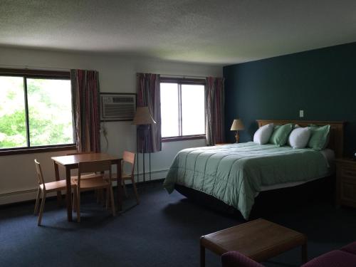a hotel room with a bed and a table and two windows at AmericInn Motel - Monticello in Monticello