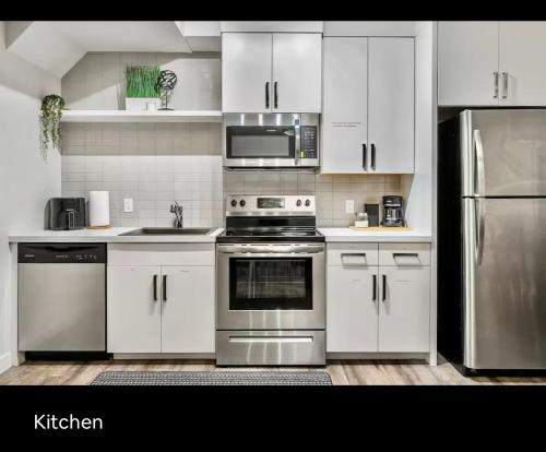 a kitchen with white cabinets and stainless steel appliances at Brand new suite with parking pad at the back in Calgary