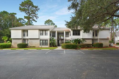 a white house with a parking lot in front of it at Central Condo, Community Pool and Gym, 10 Min to East Beach in Saint Simons Island