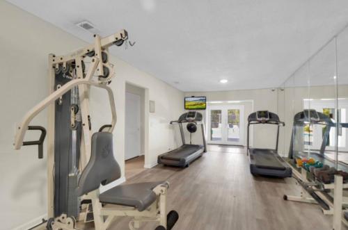 a gym with several tread machines in a room at Central Condo, Community Pool and Gym, 10 Min to East Beach in Saint Simons Island