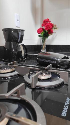 a stove top with a vase with a rose on it at Apto 1qt a 200mts da praia do Forte in Cabo Frio