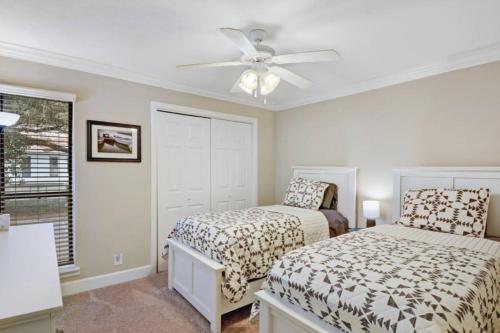a bedroom with two beds and a ceiling fan at Central Condo, Community Pool and Gym, 10 Min to East Beach in Saint Simons Island