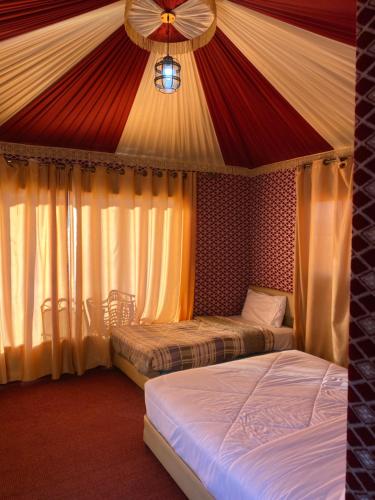 two beds in a room with a red and white tent at Katy Camp Wadi Rum in Wadi Rum