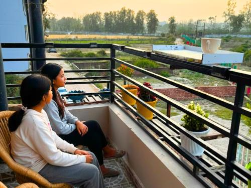 two women sitting on a balcony looking at plants at Spatii Apartment in Rishīkesh