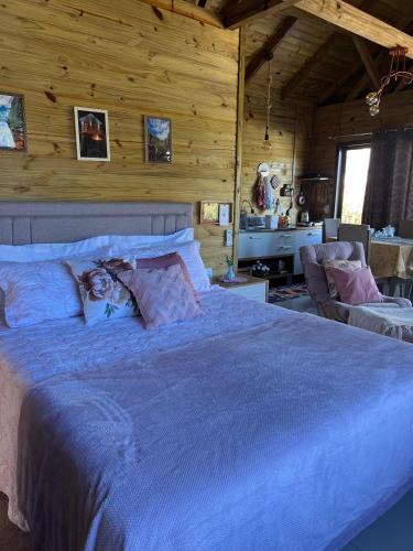 a bedroom with a large bed in a room with wooden walls at Tiny House Canjerana in Praia Grande