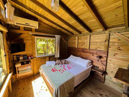 a bedroom with a bed in a wooden cabin at Pousada Vale da Magia in Praia do Rosa
