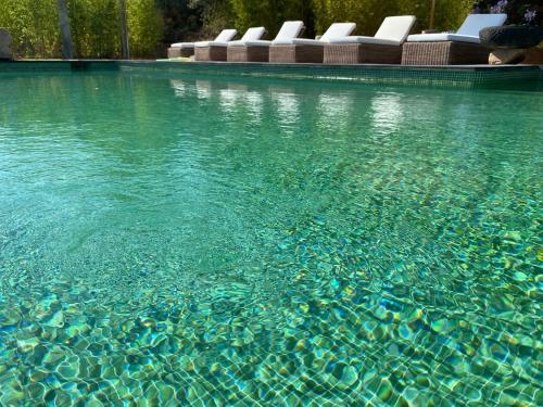 a pool of clear blue water with lounge chairs at Casa Bali Costa Brava in Palafrugell