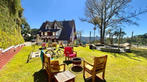 a group of chairs sitting in the grass in front of a house at Pousada Hortelã Village in Campos do Jordão