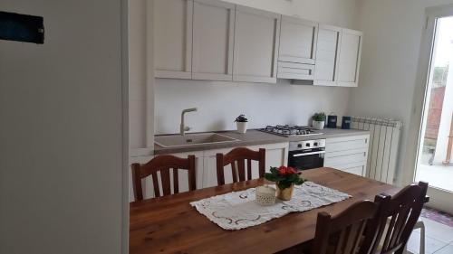 a kitchen with a wooden table with chairs and a sink at Casa Dema in Lucugnano