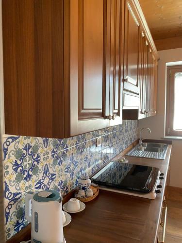 a kitchen with wooden cabinets and blue and white tiles at Cascina Nuova in Mombasiglio