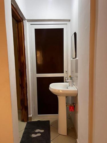 a bathroom with a white sink in front of a door at 1 bedroom apartment in shanzu near pride inn resort in Mombasa