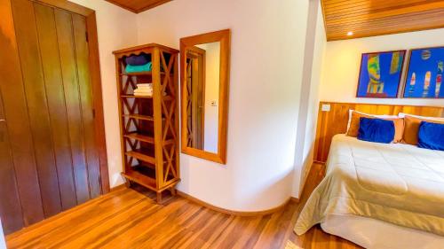 a bedroom with a bed and a mirror and a shelf at Pousada Hortelã Village in Campos do Jordão