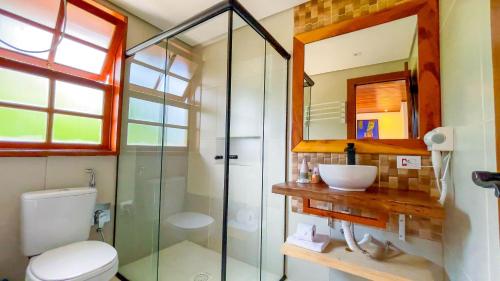 a bathroom with a toilet and a glass shower at Pousada Hortelã Village in Campos do Jordão
