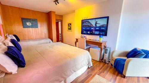 a bedroom with a bed and a desk and a tv at Pousada Hortelã Village in Campos do Jordão