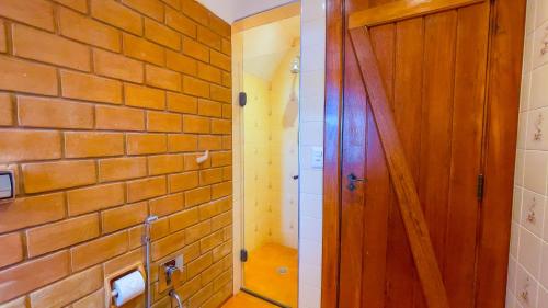 a bathroom with a brick wall and a wooden door at Pousada Hortelã Village in Campos do Jordão