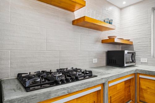 a kitchen with a stove and a microwave at Aruba Comfort Retreat 2br W Pool, Bbq & Gated in Pos Abao