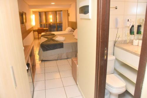 a bathroom with a bed and a toilet in a room at Luxo na Beira Mar - Beach Class Executive 105 in Recife