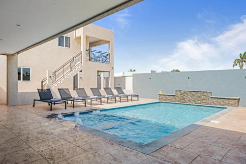 a swimming pool with chairs and a house at Aruba Comfort Retreat 2br W Pool, Bbq & Gated in Pos Abao