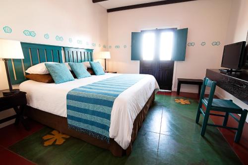 a bedroom with a bed with blue pillows and a television at Hotel Isla de Flores in Flores
