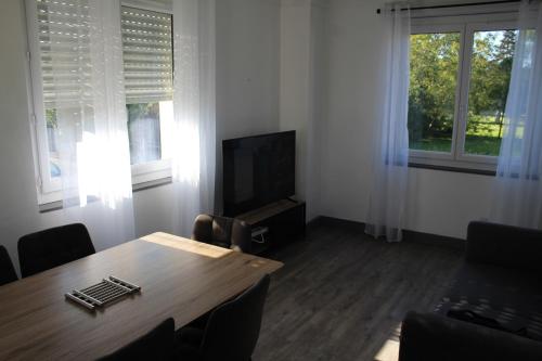 a living room with a table and a television at Le Nid - 2 Bedrooms - Myra Conciergerie in Gan