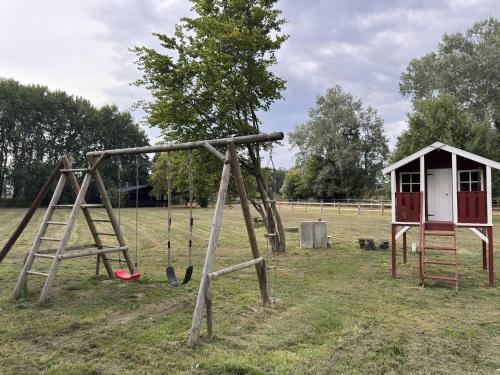 an old swing set in a field with a shed at Blockhaus mitten in der Natur in Eschede
