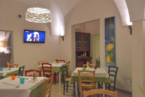 San Donato di LecceにあるAgriturismo Puntarelleのテーブルと椅子、壁掛けテレビ付きのレストラン