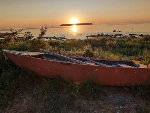 a boat sitting on the shore of a beach at sunset at 4 star holiday home in Klintehamn in Klintehamn