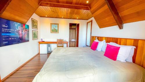 a bedroom with a large bed with red pillows at Pousada Hortelã Village in Campos do Jordão
