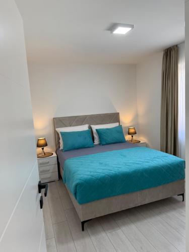 a bedroom with a bed with blue sheets and two lamps at Emily in Slime