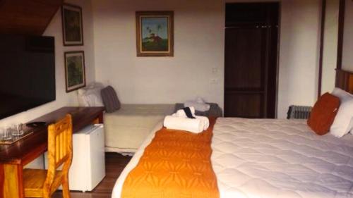 a bedroom with a large bed and a desk and a desk at Pousada Hortelã Village in Campos do Jordão