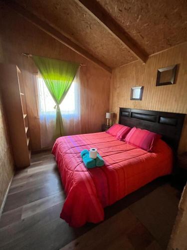 a bedroom with a bed with a red blanket and a window at Cabañas 4 PIA in Puerto Tranquilo