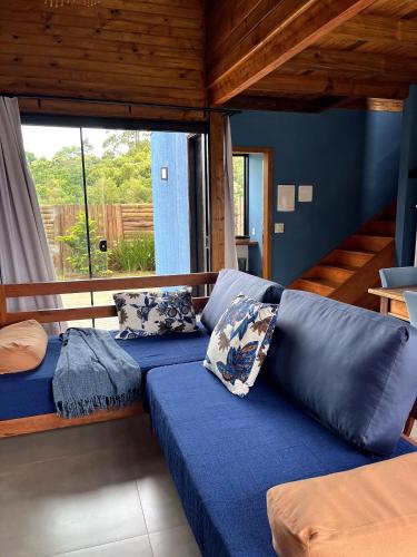 a living room with a blue couch with pillows at Casa com Banheira, Piscina e Quadra de Areia in Praia do Rosa