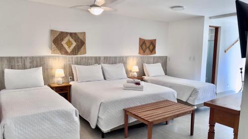a hotel room with two beds and a table at Bella Buzios Apartamentos in Búzios