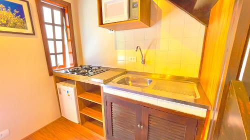 a small kitchen with a sink and a stove at Pousada Hortelã Village in Campos do Jordão