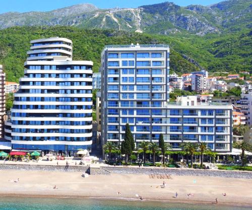 two tall buildings on a beach next to a beach at Azure Coast Residence Budva in Becici
