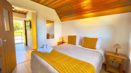 a bedroom with a large bed with yellow pillows at Pousada Hortelã Village in Campos do Jordão