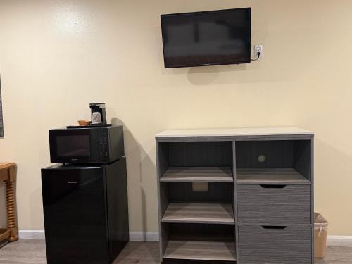 a room with a tv and a tv stand with a microwave at Anaheim National Inn in Anaheim