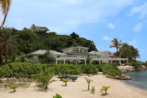 a house on a beach with trees and the water at East End Antigua Boutique Hotel in Willikies