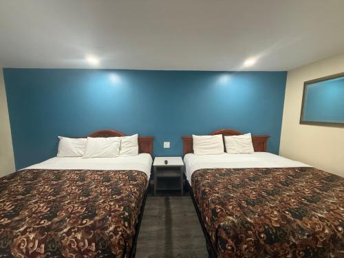 two beds in a hotel room with a blue wall at Anaheim National Inn in Anaheim