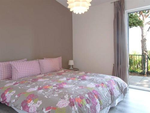 a bedroom with a bed with a floral bedspread and a window at Les Mini-Villas de Santa Giulia in Porto-Vecchio