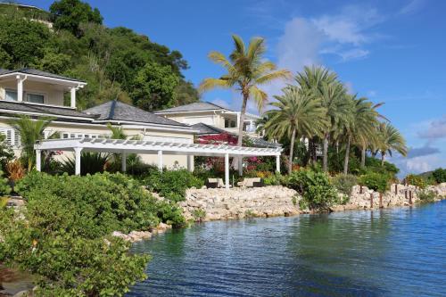 a house next to a river with palm trees at East End Antigua Boutique Hotel in Willikies