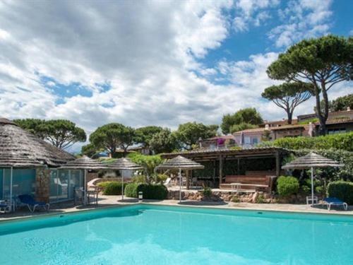 a large swimming pool with umbrellas and a house at Les Mini-Villas de Santa Giulia in Porto-Vecchio