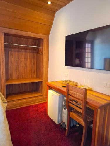 a room with a desk with a bench and a television at Pousada Hortelã Village in Campos do Jordão
