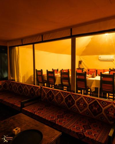 a dining room with chairs and a table in a tent at Dounia Luxury Camp in Merzouga