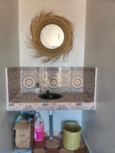 a bathroom sink with a mirror on a wall at The dune camp in Mhamid
