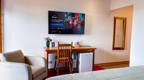 a room with a desk with a chair and a tv at Pousada Hortelã Village in Campos do Jordão