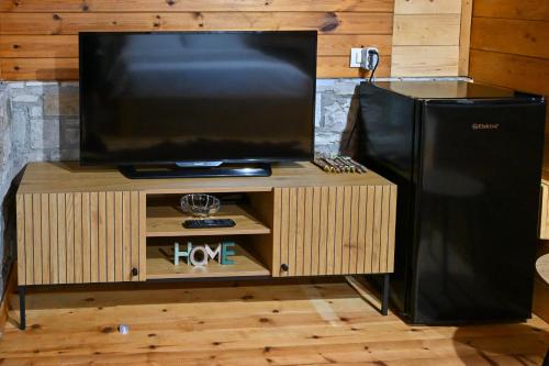 a flat screen tv on a stand with a black refrigerator at Airport Comfort Nest in Kamëz